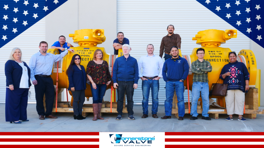 Team members of cornerstonevalve standing in front of two huge yellow valves,